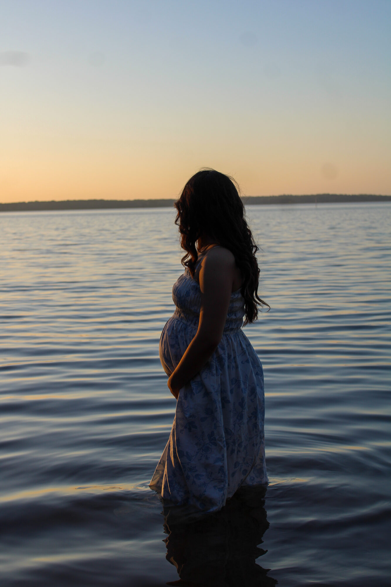 Maternity silhouette at sunset by the water