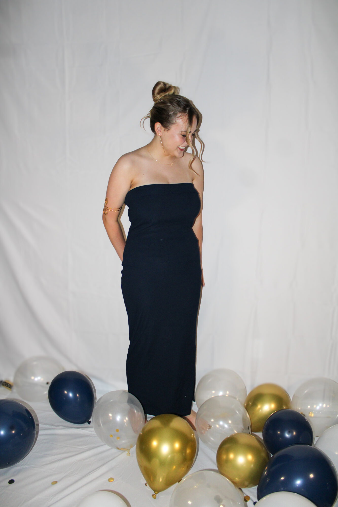 Grad-year portrait in a navy gown with balloons