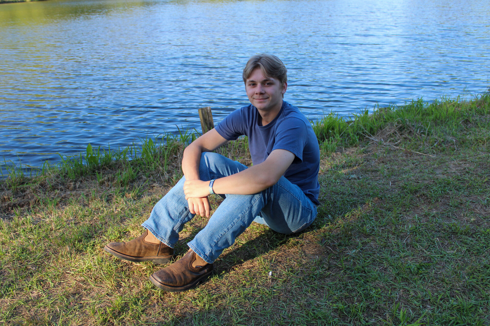 Black and white portrait of a young man with a puppy by the water