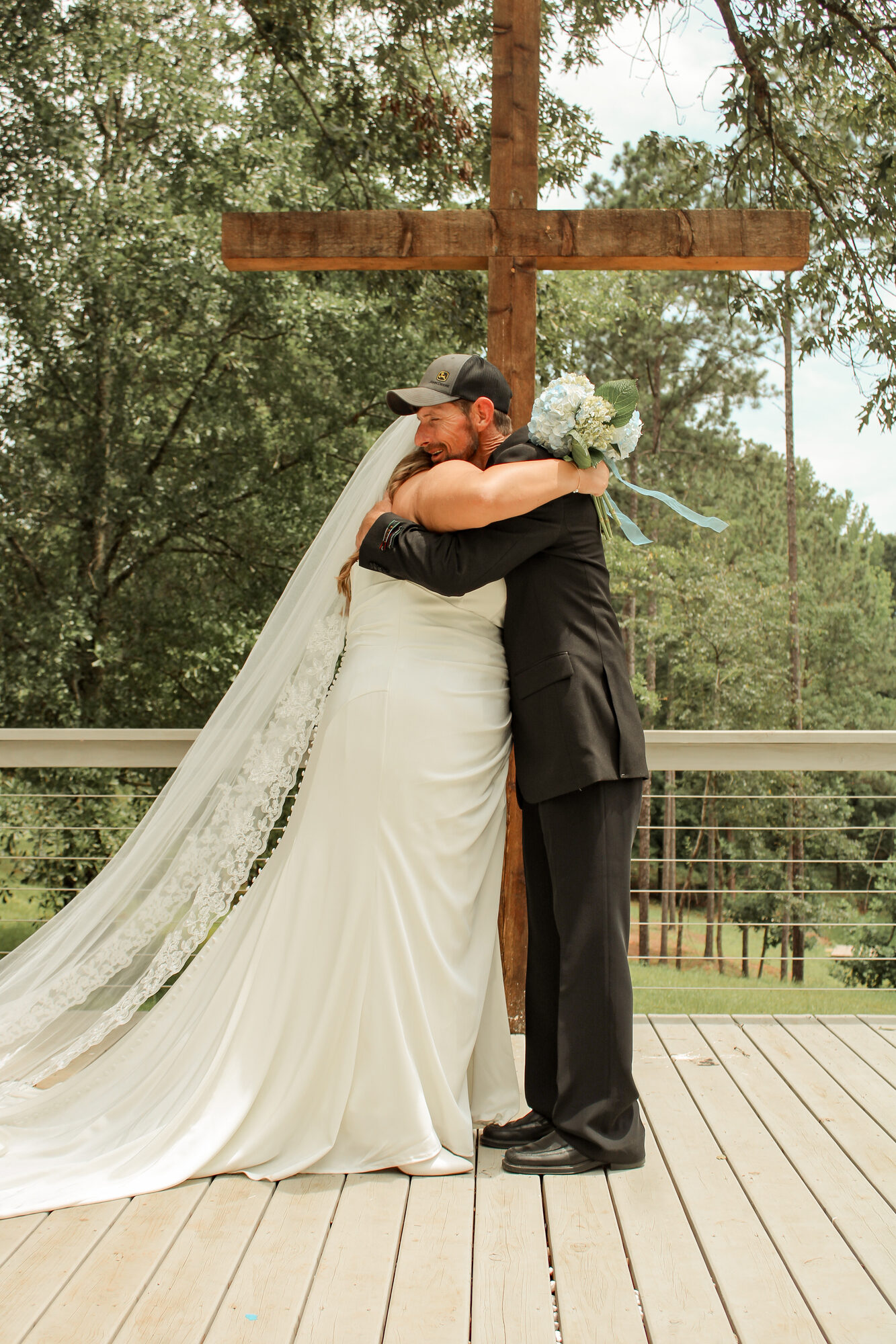 Emotional embrace beside a wooden cross at a wedding